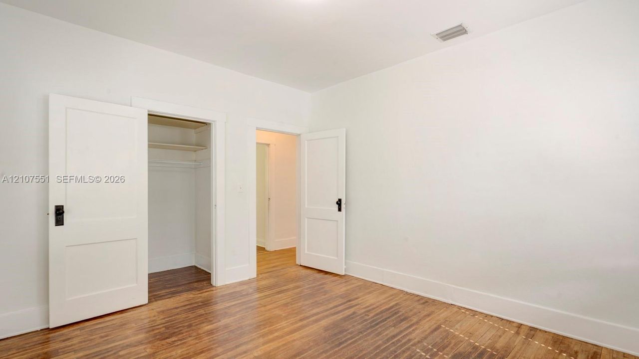 Wood-finish flooring, two-panel interior doors with matte black hardware, and integrated closet shelving