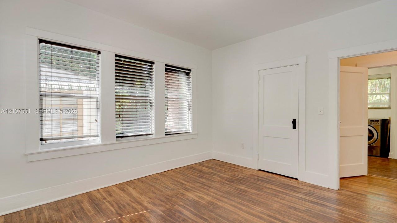 Neutral interior featuring wood-finish flooring, white walls, and triple-pane window configuration with classic millwork trim