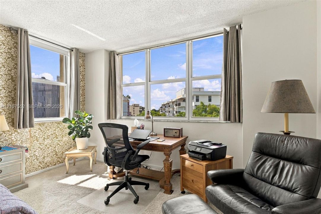 Room featuring large windows with natural light, patterned wall covering, and neutral carpeting