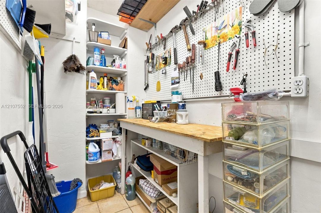 Built-in shelving unit, wall-mounted pegboard organization system, and wooden workbench with lower storage compartments