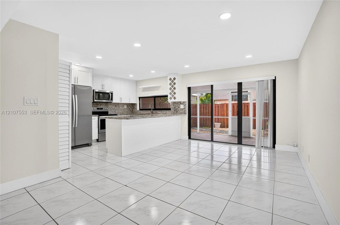 Kitchen featuring white cabinetry, stone-surface countertops, stainless steel appliances, recessed lighting, and tile flooring