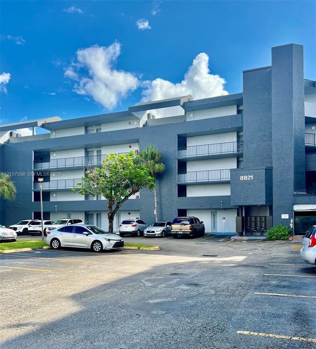 Multi-story exterior featuring a contemporary blue facade, private balconies, and dedicated surface parking