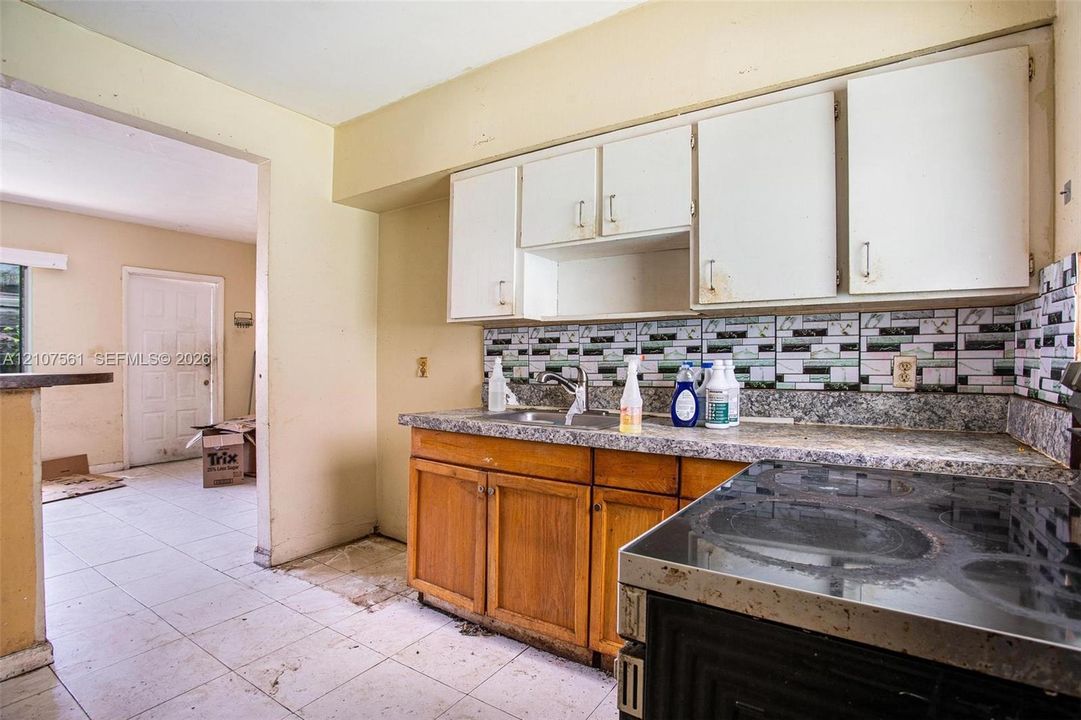 Kitchen featuring wood cabinetry, stone-finish countertops, tile backsplash, and a ceramic cooktop