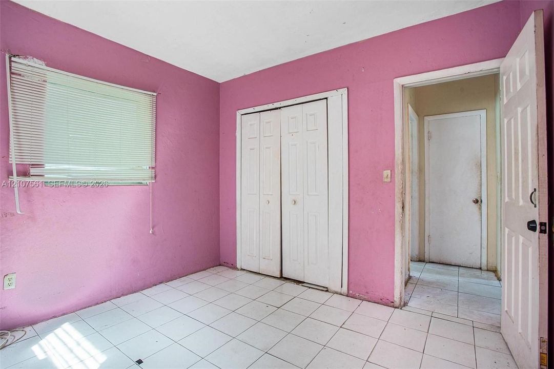 Room featuring white tile flooring, white bi-fold closet doors, and white interior doors with hardware