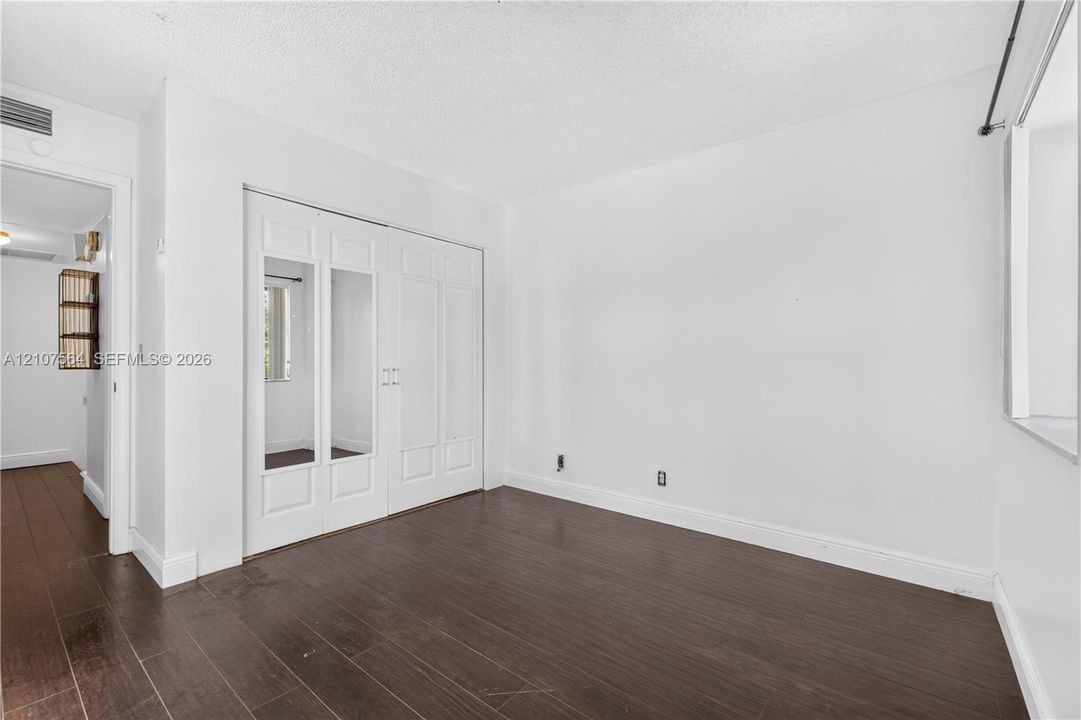 Wood-finish flooring and double-door closet with inset mirror panels
