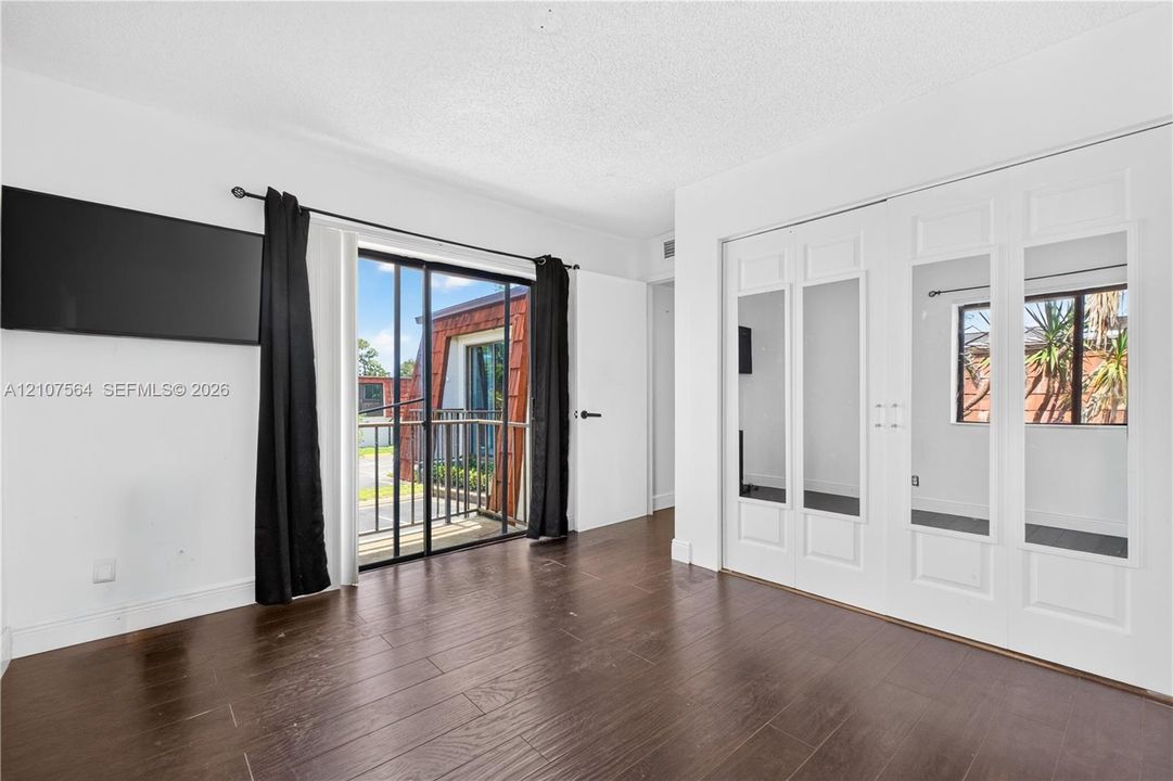 Wood-finish flooring, floor-to-ceiling glass sliding doors, and a double-panel closet with integrated full-length mirrors