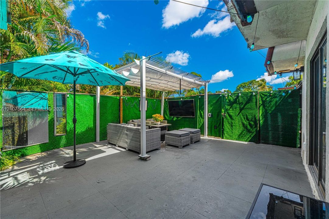 Concrete patio featuring a metal-frame pergola with a retractable shade canopy and privacy fencing