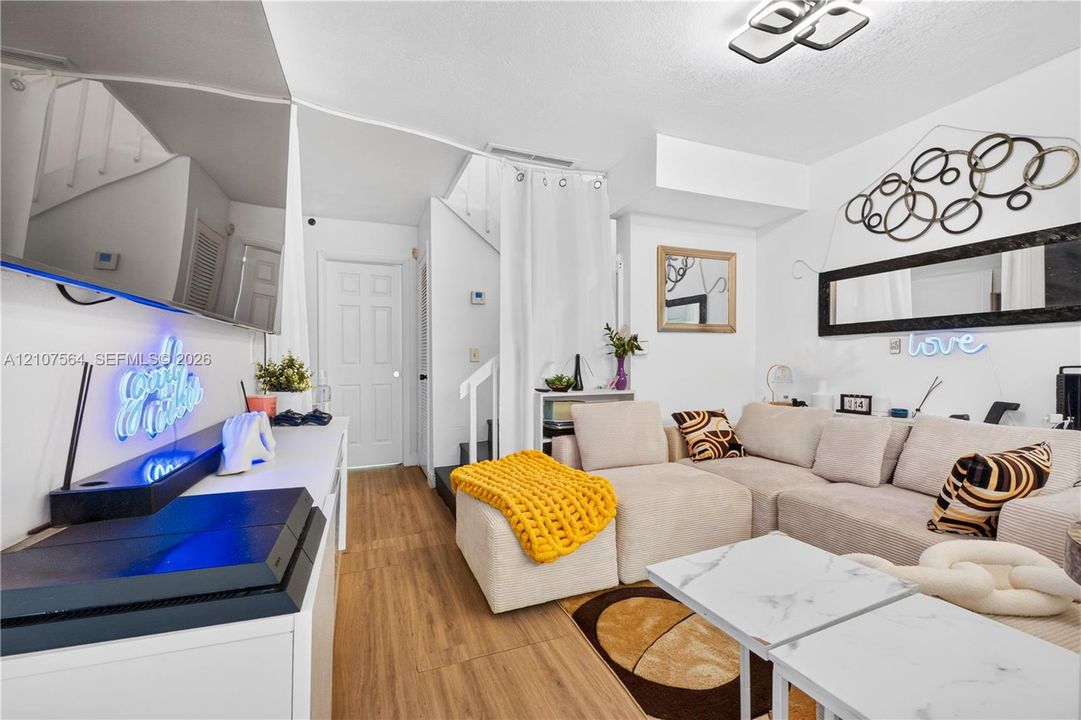 Interior space featuring wood-finish flooring, white paneled interior doors, and geometric flush-mount ceiling lighting