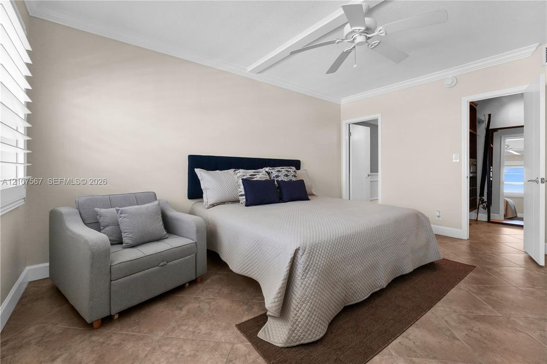 Neutral-toned walls with crown molding, diagonal tile flooring, multi-blade ceiling fan, and white shutter window treatments