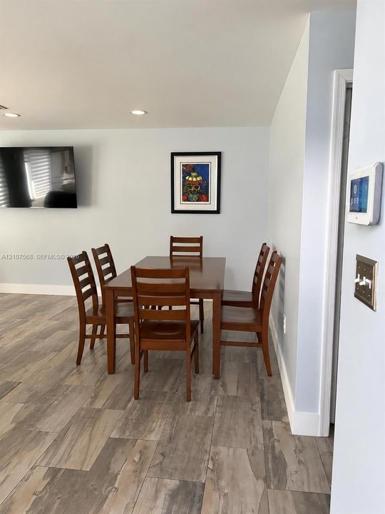 Wood-finish flooring, recessed ceiling lighting, and a wall-mounted smart home control panel