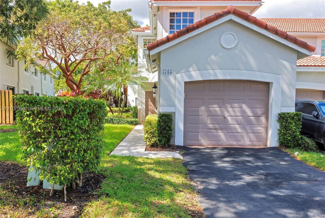 Two-story exterior featuring a clay tile roof, stucco facade, and an attached single-car garage