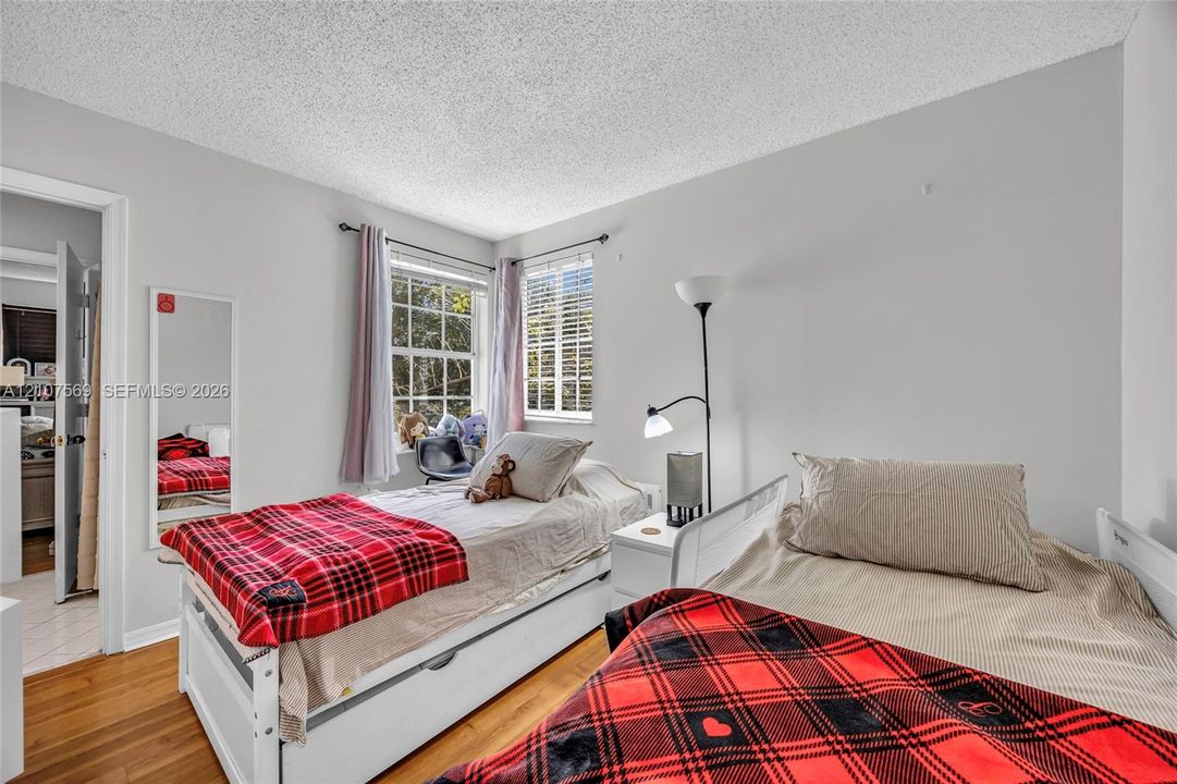 Neutral-toned room featuring wood-finish flooring and dual windows with horizontal blinds