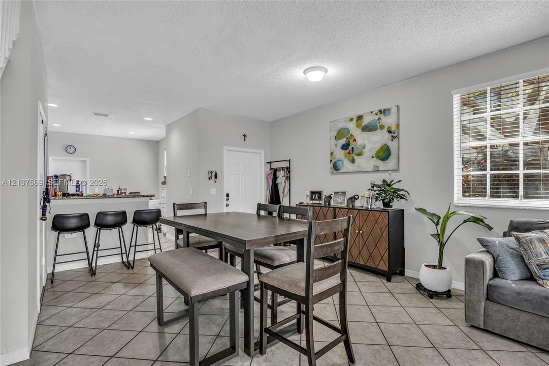 Open-concept interior featuring large-format diagonal tile flooring, a breakfast bar with stone-surface countertop, and multi-pane window