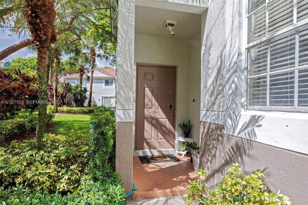Covered entryway featuring a solid-panel entry door, exterior recessed lighting, and a multi-pane window with integrated blinds
