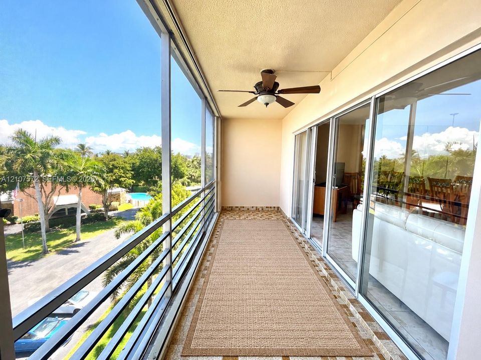 Screened-in balcony featuring metal railing, tiled flooring, and a ceiling fan