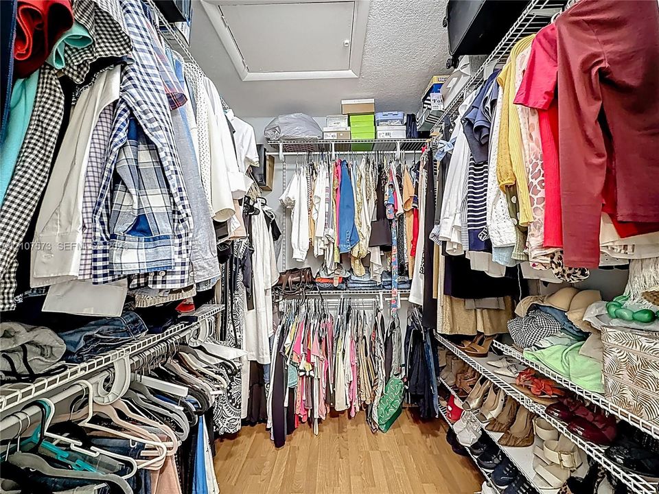 Walk-in closet featuring tiered wire shelving and wood-finish flooring