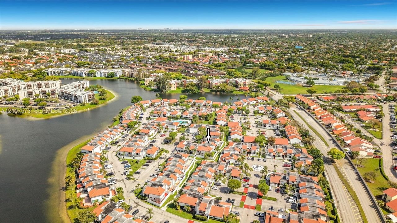 Aerial perspective of residential community featuring multi-unit structures with terracotta-style roofs and mature landscaping