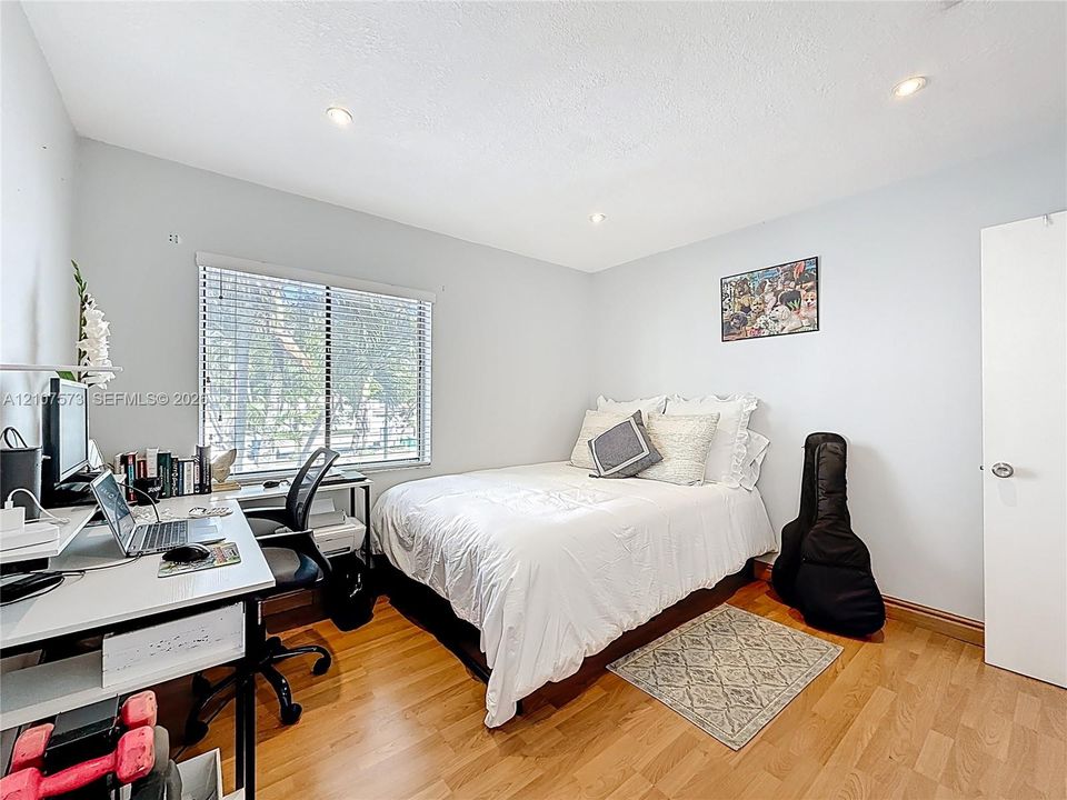 Room featuring wood-finish flooring, recessed lighting, and a window with horizontal blinds