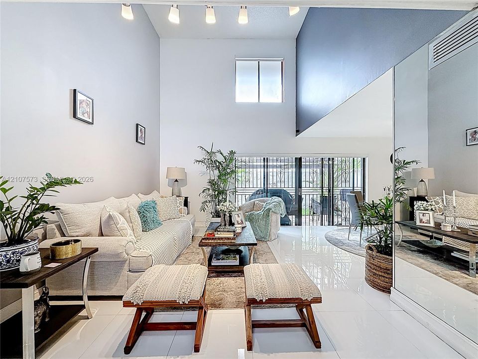 Double-height ceilings, polished tile flooring, full-wall mirrors, recessed track lighting, and sliding glass doors with exterior access