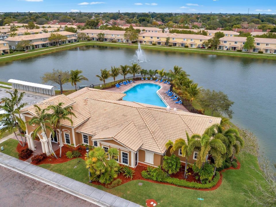 Community clubhouse featuring a tile roof, an exterior pool, and surrounding water frontage