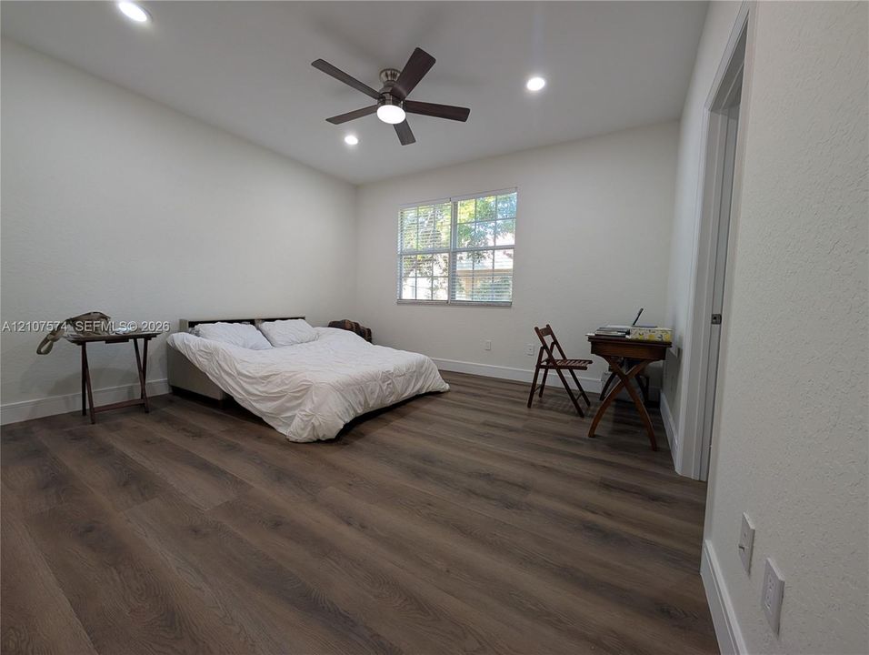 Room featuring wood-finish flooring, recessed lighting, a multi-blade ceiling fan with integrated light, and a double-pane window