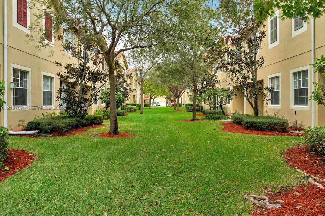 Common grounds featuring expansive lawn, mature shade trees, and manicured shrubbery with red mulch landscape beds