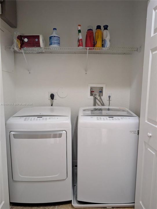 Laundry alcove featuring white top-load washer and dryer set, white wire shelving, and dedicated water and electrical hookups