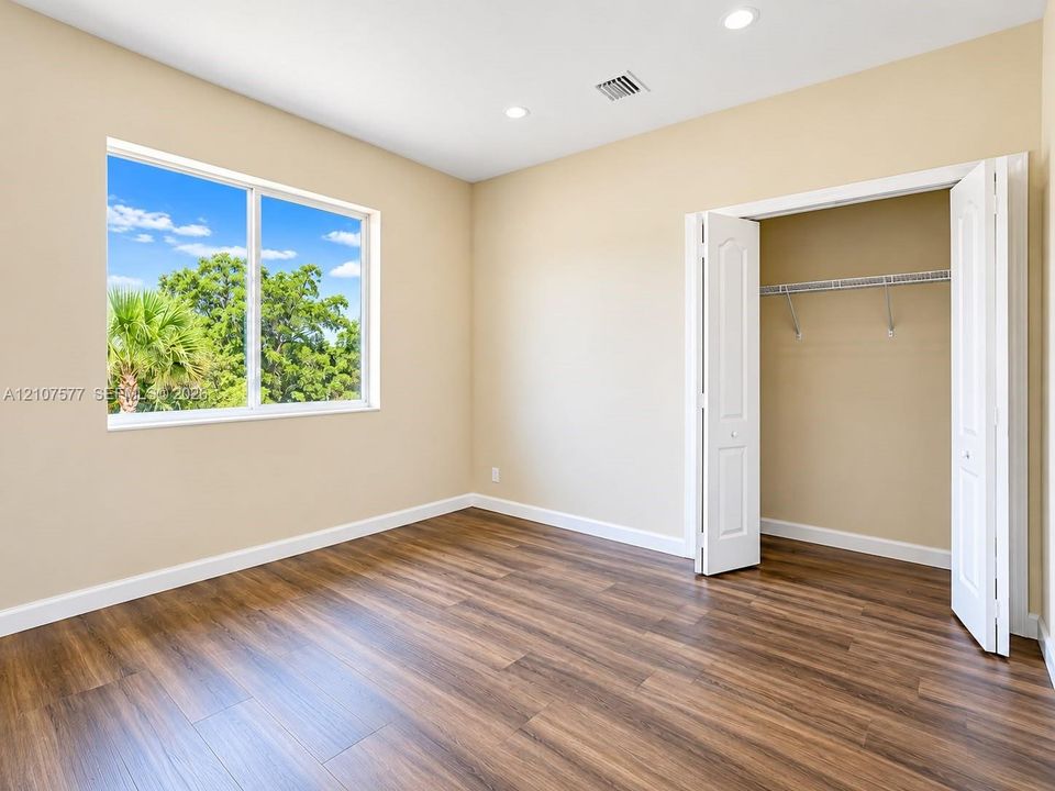 Room interior featuring wood-finish flooring, recessed lighting, a large picture window, and a closet with bifold doors