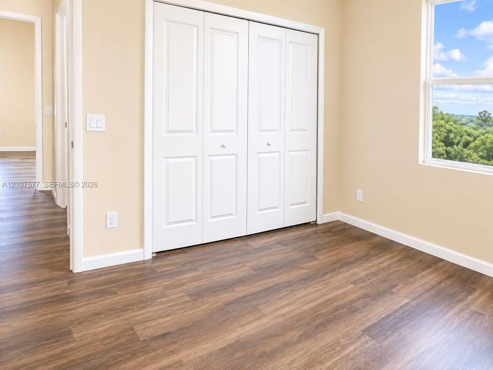 Wood-finish flooring, white paneled bi-fold closet doors, and single-pane window