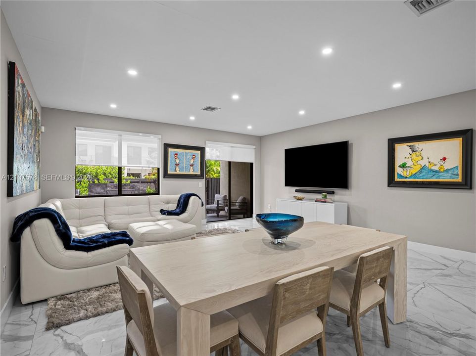 Open-concept interior featuring large-format tile flooring, recessed ceiling lighting, and sliding glass doors