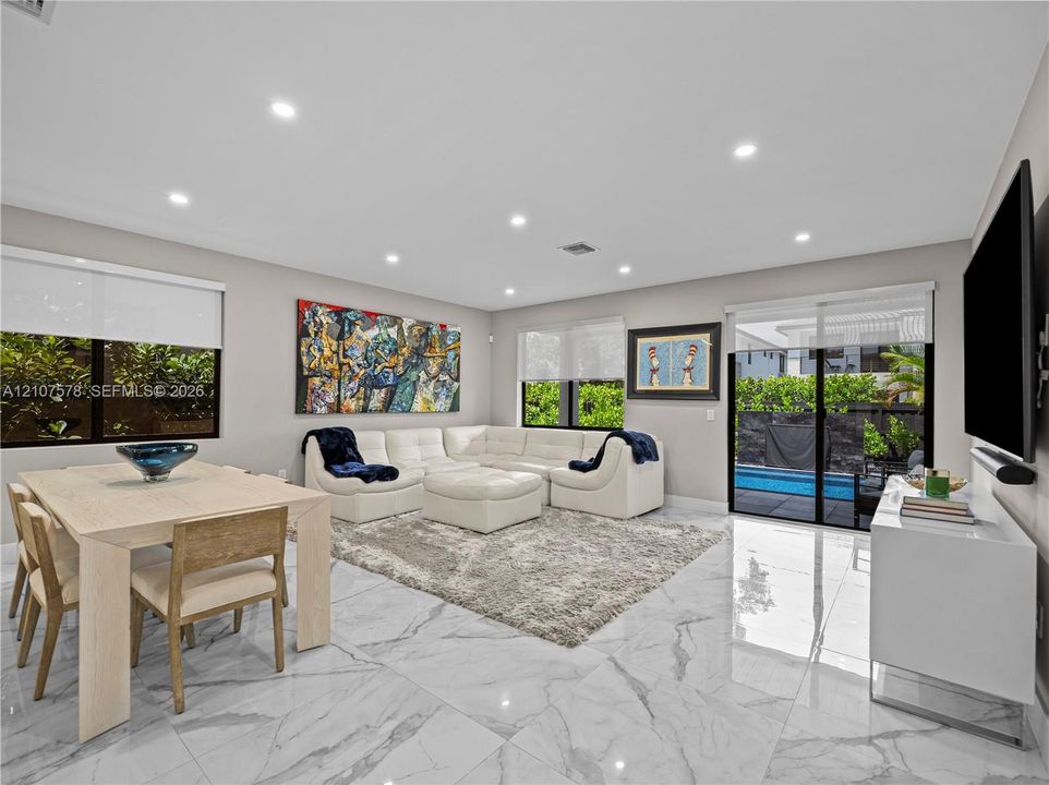 Open-concept living space featuring high-gloss large-format floor tiling, recessed lighting, and sliding glass doors with exterior patio and pool access