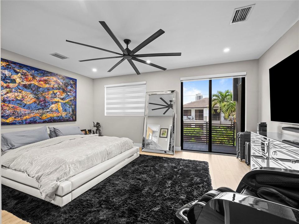 Expansive room featuring recessed lighting, a multi-blade matte black ceiling fan, wood-finish flooring, and a large sliding glass door providing access to a private balcony