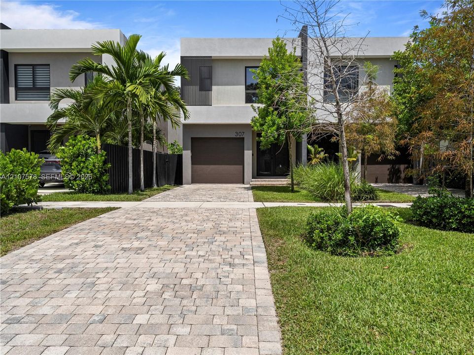 Contemporary two-story exterior featuring a smooth stucco facade, paver driveway, and an integrated single-car garage
