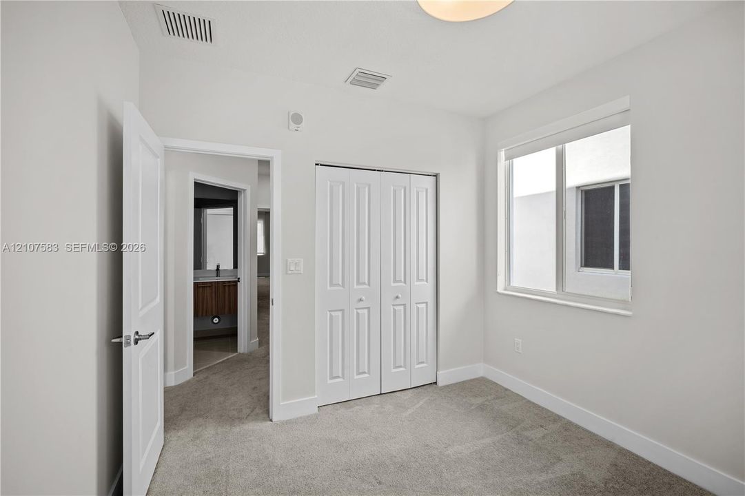 Neutral-toned carpeted flooring, bi-fold closet doors, and a double-pane window