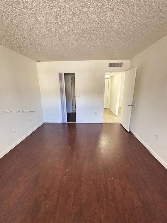Interior space featuring wood-finish flooring, white walls, and a textured ceiling