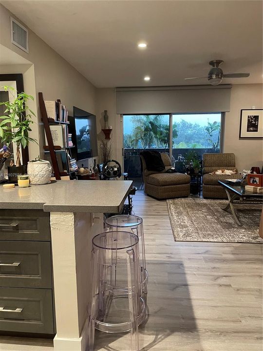 Kitchen island with a solid surface countertop, gray cabinetry, wood-finish flooring, recessed ceiling lighting, and sliding glass doors