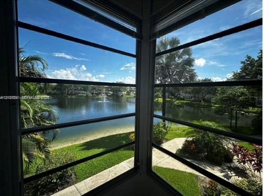 Corner window enclosure featuring aluminum-framed horizontal jalousie windows, integrated blinds, and exterior water frontage with landscaped grounds