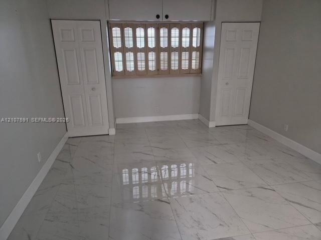 Polished stone-look tile flooring, dual closets with solid-core panel doors, and window shutters