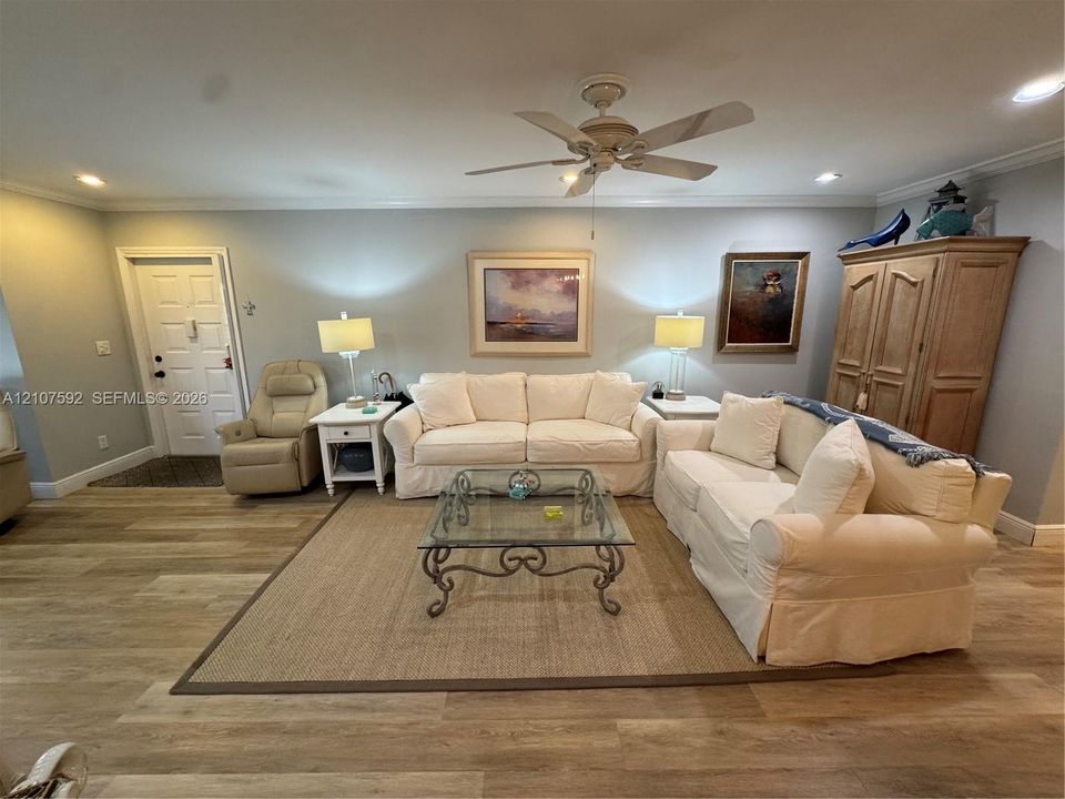 Living area featuring wood-finish flooring, a ceiling fan with integrated lighting, and recessed ceiling lights