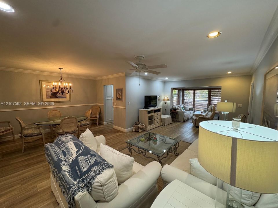 Open-concept interior featuring wood-finish flooring, crown molding, chair rail trim, recessed lighting, and a multi-pane bay window