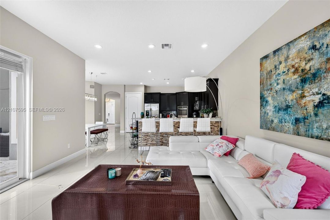 Kitchen featuring dark cabinetry, recessed lighting, and a stone-tiled breakfast bar, complemented by glossy tile flooring and an arched entryway