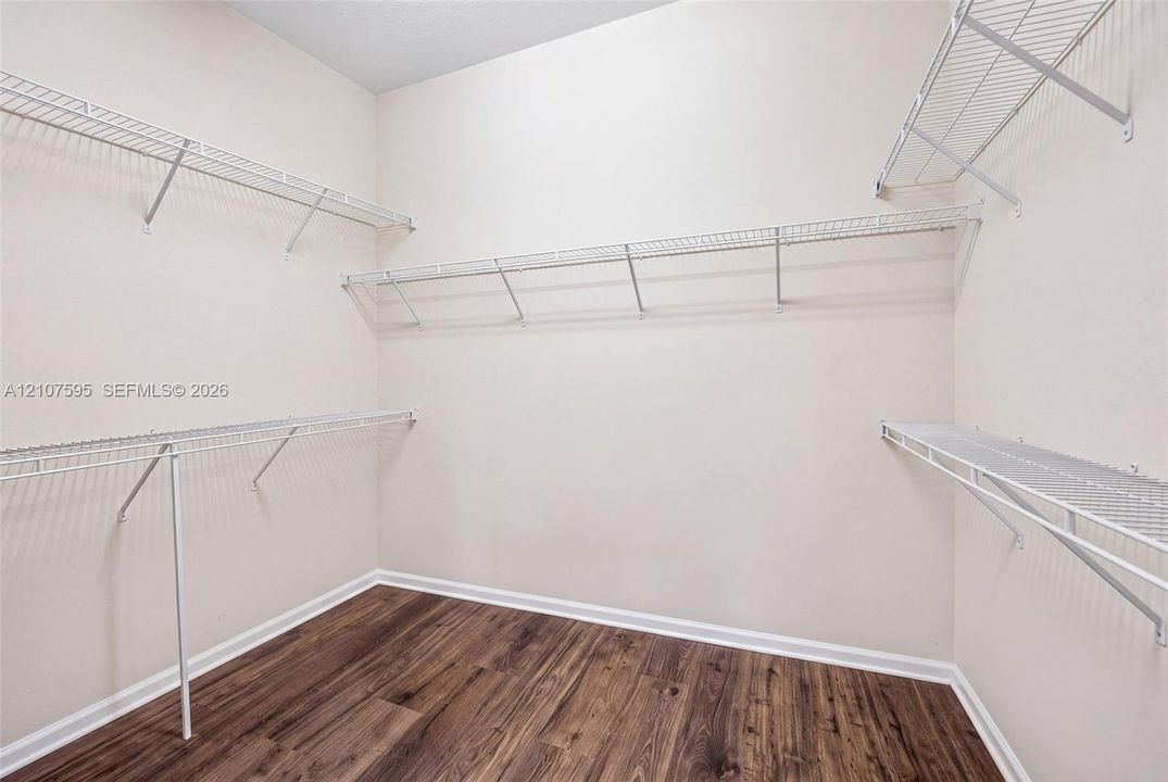 Walk-in closet featuring wood-finish flooring and tiered white wire shelving