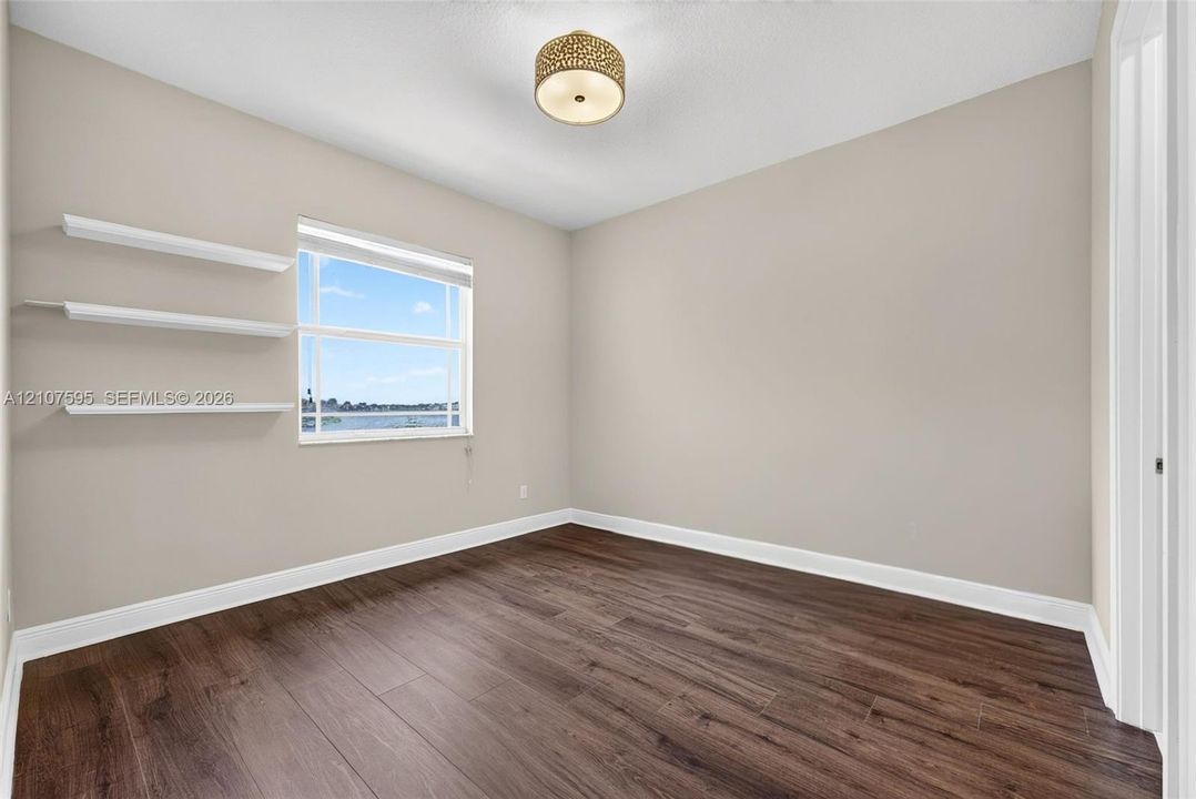 Wood-finish flooring, neutral wall tones, built-in shelving, energy-efficient window, and decorative semi-flush mount lighting