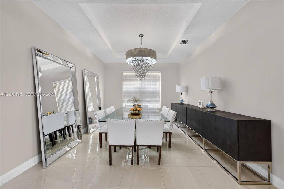 Tray ceiling featuring recessed lighting, polished tile flooring, and a central tiered crystal chandelier