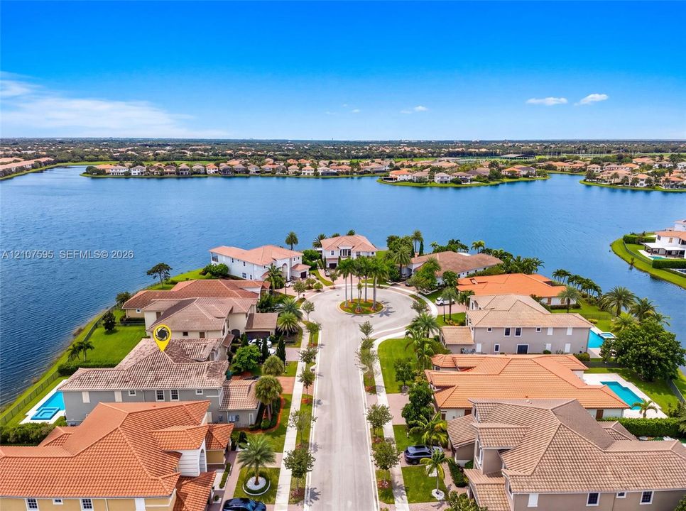 Waterfront property featuring tile roofing, concrete paved cul-de-sac, and landscaped palm trees