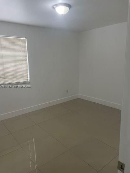 Neutral interior room featuring large-format tile flooring, crisp white walls, and a recessed ceiling light fixture