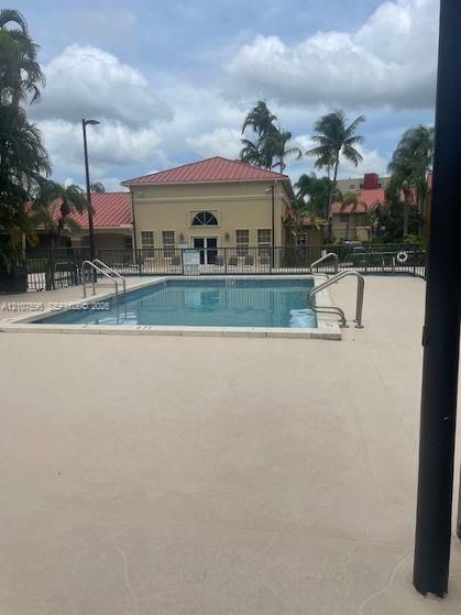 In-ground swimming pool featuring a concrete deck, metal handrails, and surrounding fencing