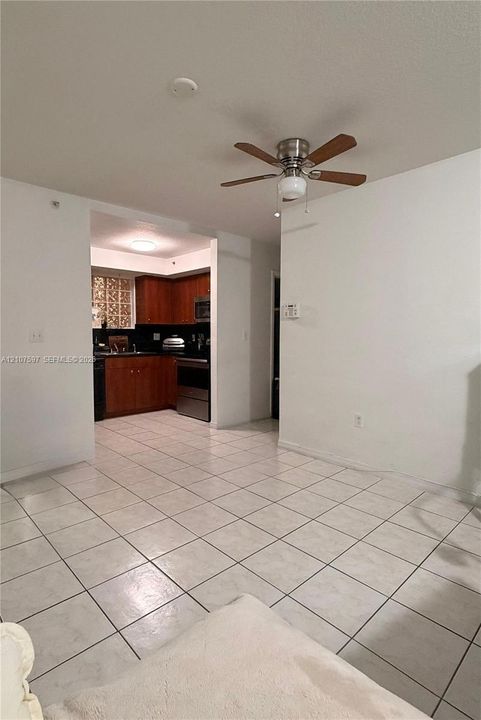 Tile flooring throughout, wood-finish cabinetry, stainless steel kitchen appliances, glass block window detailing, and a multi-blade ceiling fan