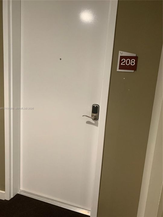 Entry door featuring a white finish, integrated metal deadbolt with electronic keypad access, and a centered peephole