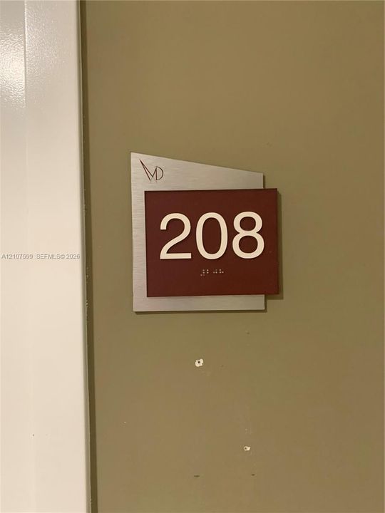 Brushed metal plaque featuring white numerical signage and integrated tactile characters
